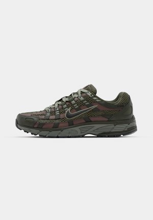 Dunkelgrüner Sportschuh mit Mesh-Einsätzen, roten Akzenten und strukturiertem Profil. Verfügt über einen gepolsterten Kragen und ein kontrastierendes Schnürsystem.