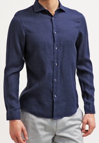 Marinblå långärmad skjorta med knappar, tillverkad av texturerat tyg, med en standardkrage och fem knappar framtill.