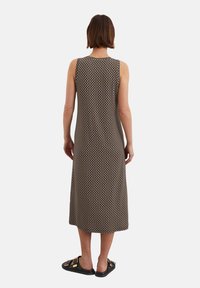 Ärmelloses Midi-Kleid in Braun mit geometrischen Mustern, aus weichem Stoff gefertigt. Hat einen geraden Schnitt und einen runden Halsauschnitt. Wird mit schwarzen Sandalen getragen.