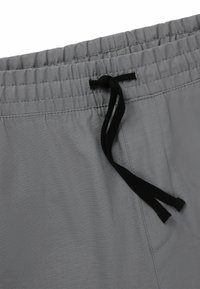 Grå shorts lavet af letvægtsstof, med en elastisk talje og en sort snor, samt detalje med sidelommer.