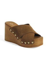 Sandales à talon compensé marron avec un design de brides croisées en suede doux, ornées de clous dorés et d'une base en bois.