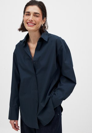 Navy blue button-up shirt made of cotton, featuring a relaxed fit, long sleeves, and a wide collar. Smooth texture with no patterns.