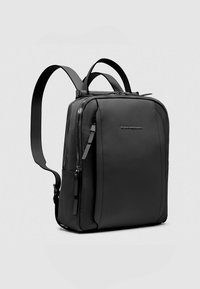 Zwarte leren rugzak met twee verstelbare schouderbanden, een hoofdvak met ritssluiting en een slank, rechthoekig ontwerp.