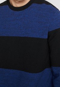 Sweter dzianinowy z poziomymi paskami w ciemnoniebieskim i czarnym kolorze. Okrągły dekolt oraz teksturowany materiał o miękkim wykończeniu.