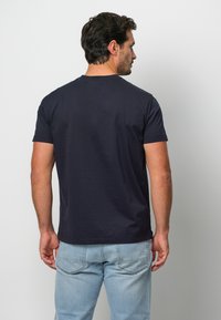 Marinblå bomulls t-shirt med kort ärm och rund halsringning, med en slät yta och enkel design, bärs tillsammans med ljusblå jeans.