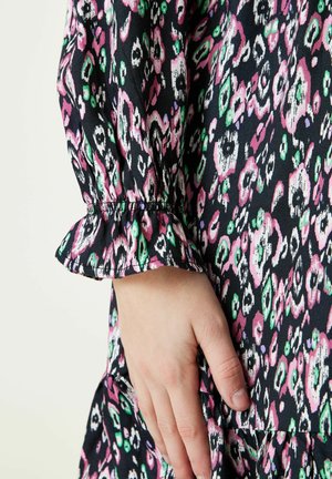 Černé šaty z tkaniny s barevným abstraktním potiskem v růžové, zelené a bílé. Mají nařasené rukávy s volánovými manžetami a volný střih.