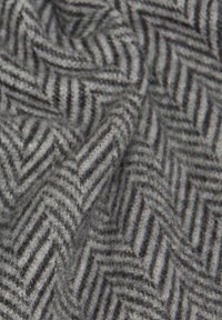 Grijs stof met een herringbone-patroon, gemaakt van een zachte, geweven wolmix. Bevat afwisselende dondergrijze en lichtgrijze strepen in een zigzagontwerp.