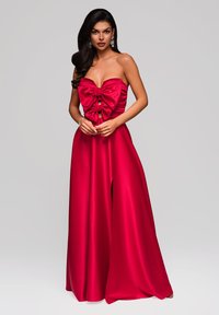 Jumpsuit in raso rosso con design senza spalline, dettaglio a fiocco sul petto e pantaloni a gamba larga. Texture liscia e silhouette fluida.