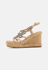 Sandali con zeppa beige con suola in corda stile espadrilles, con un adornamento decorativo in gioiello sulle cinghie e una fibbia metallica.