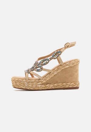 Beige wedge sandals with an espadrille-style rope sole, featuring a decorative jewel embellishment on the straps and a metallic buckle.