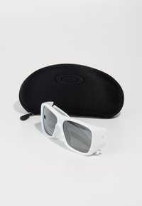 Óculos de sol brancos com lentes cinzas apresentam uma armação retangular grossa e design angular. Estojo protetor preto incluído, com detalhe do logótipo.