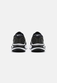 Sneakers Nike con un design nero e verde oliva, con una parte superiore texturizzata, una suola intermedia bianca e dettagli a motivo sul tallone.