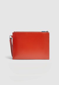 Bolso clutch de cuero rojo con forma rectangular plana, cierre con cremallera y una correa adjunta. Textura suave con detalles mínimos de hardware.