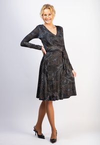 Musta kietaisumekko pitkillä hihoilla, jossa on hopea- ja pronssivärinen paisley-kuvio. Valuava hame, vyötärö hihnalla, joka on samaa kangasta.