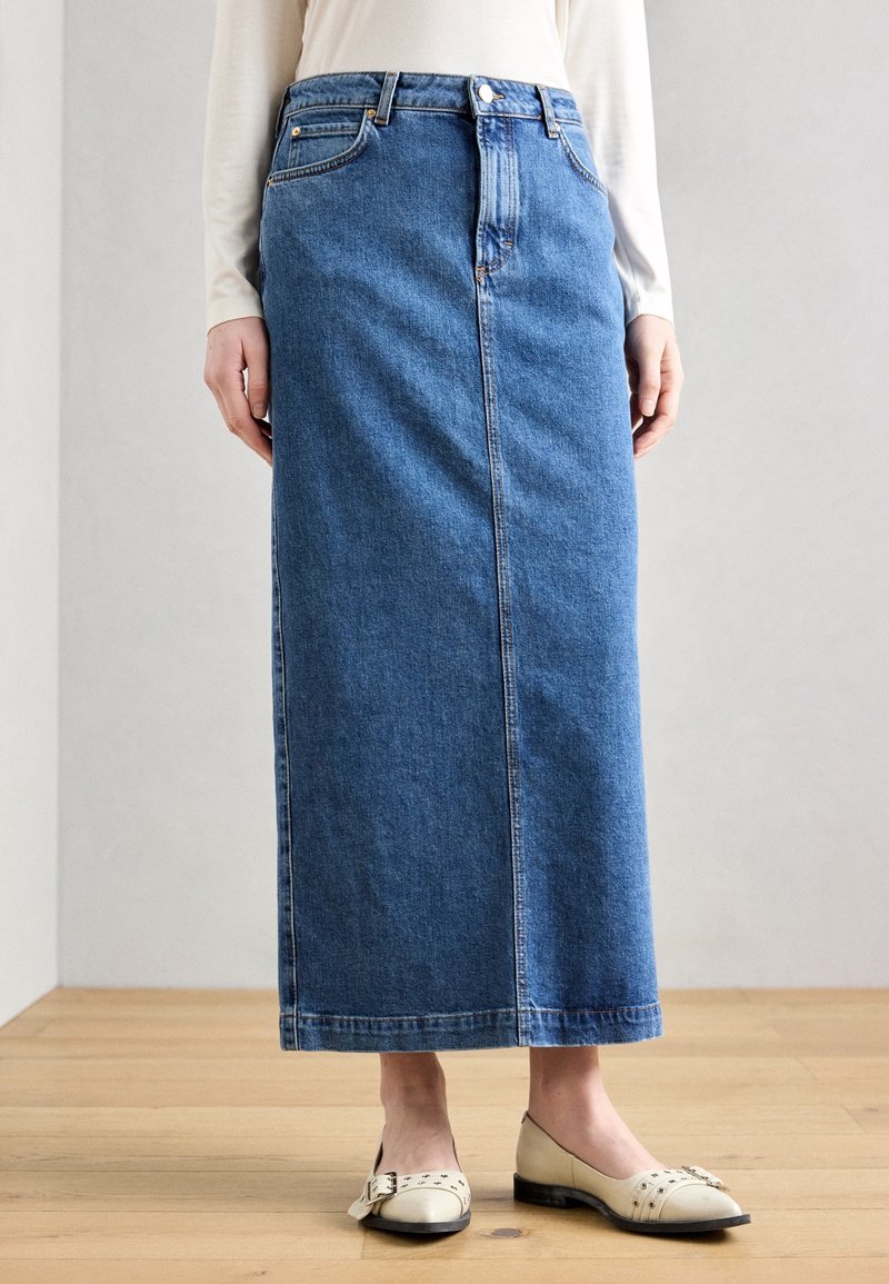 Falda maxi de mezclilla en azul medio con corte recto, diseño de cinco bolsillos, cierre frontal de botones y detalles de costura sutiles.