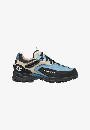 Zapato de senderismo de corte bajo en beige, azul y negro con cordones negros y suela resistente, con la marca Garmont en el panel lateral.