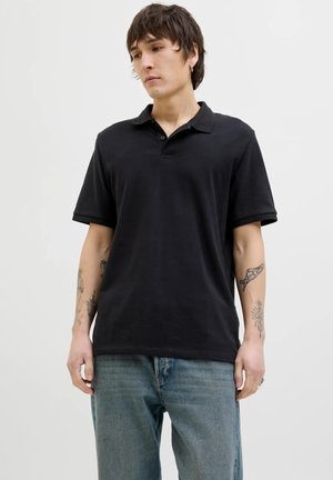 Polo shirt nero a maniche corte con colletto, realizzato in tessuto morbido. Presenta una vestibilità rilassata, cuciture sottili e una classica patta a due bottoni.