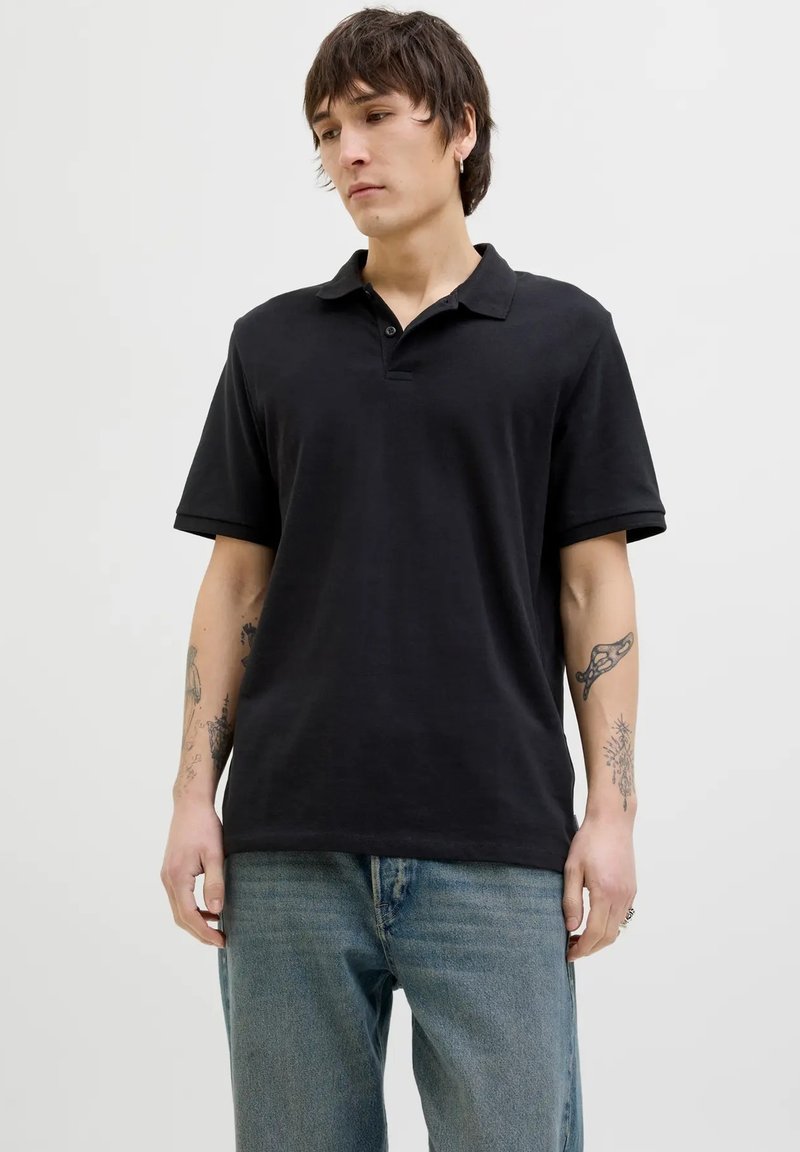 Polo shirt nero a maniche corte con colletto, realizzato in tessuto morbido. Presenta una vestibilità rilassata, cuciture sottili e una classica patta a due bottoni.