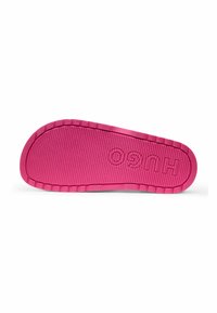 Rubber shoe sole in bright pink. Features ridged texture and engraved 'HUGO' logo, smooth edges, and a slightly raised border.