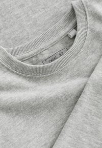 Grå sweatshirt lavet af blødt materiale, med ribbet rund hals og et mærke syet indeni. Teksturen er glat med en ensartet farve.