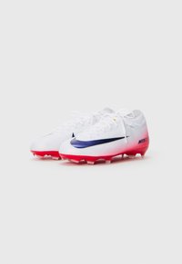 Een paar witte Nike Mercurial voetbalschoenen met rode zolen en zwarte swoosh-logo's, weergegeven vanuit een lichte hoek op een witte achtergrond.