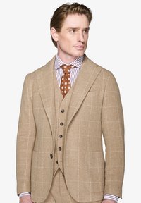 Beige ulddragt med et ternet mønster, notch krave, seks-knaps vest og et brunt polka dot slips over en stribet skjorte.