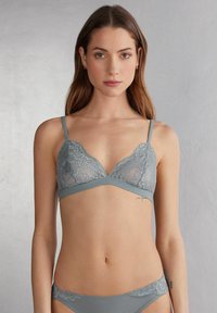 Lichtgrijze kanten bralette met verstelbare bandjes, V-hals ontwerp en een zachte onderband. Versierde kantdetails langs de cups en band.