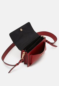 Borsa a tracolla rossa in pelle con interno nero, chiusura dorata, tracolla regolabile e scomparti multipli, mostrata aperta su sfondo bianco.