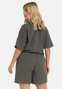 Mörkgrå, kortärmad jumpsuit i texturerad tyg med elastiskt midjeband. Lätt lös passform med en avslappnad design, lämplig för avslappnad användning.