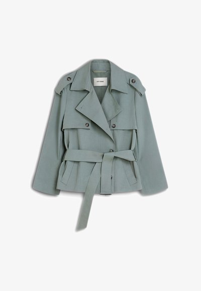 Ανοιχτοπράσινο trench coat με ζώνη, φαρδιές πέτο, κουμπωτούς ιμάντες ώμων και λεπτομέρειες με εμπρόσθιες πτυχώσεις σε λευκό φόντο.