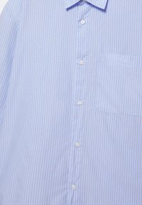 Jasnoniebieska męska koszula wizytowa z cienkimi, białymi pionowymi paskami, białymi guzikami z przodu oraz kieszenią na piersi po lewej stronie.