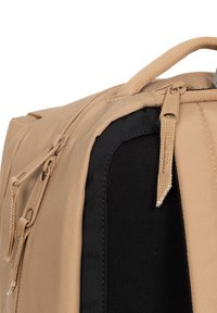 Zaino in tessuto beige con dettagli neri, dotato di doppie cerniere e superficie testurizzata. Include cuciture robuste e una maniglia per il trasporto superiore.