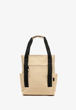 Beige schoudertas met zwarte handvatten, voorzien van een voorvak met rits, zijvakjes en een gestructureerd ontwerp met een gladde textuur.