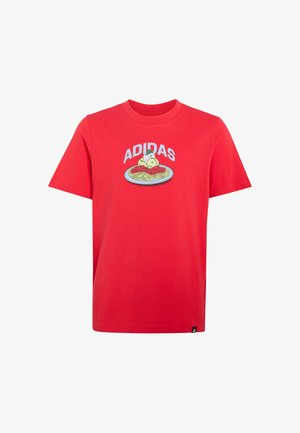 T-shirt rouge à manches courtes avec le texte « ADIDAS » au-dessus d’un visuel représentant une assiette de spaghettis et boulettes de viande à l’avant.