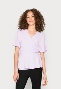 Top envolvente lavanda feito de tecido leve, com mangas curtas, bainha peplum e um detalhe de laço de um lado.