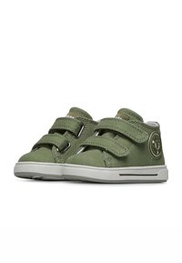 Zelené plátěné boty na nižším podpatku s dvěma nastavitelnými suchými zipy, gumovou podrážkou a kulatým logem na boku. Nízký, zaoblený design.