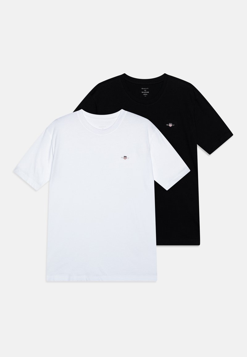 Divi crewneck T-krekli, viens balts un viens melns, izgatavoti no mīksta kokvilnas. Abiem ir neliels logo uz krūtīm kontrastējošās krāsās.