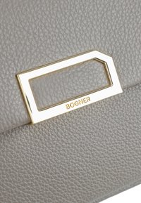 Lys grå læderhandbag med en tekstureret overflade og en gylden rektangulær hardwaredetalje med mærkenavnet "BOGNER" indgraveret.