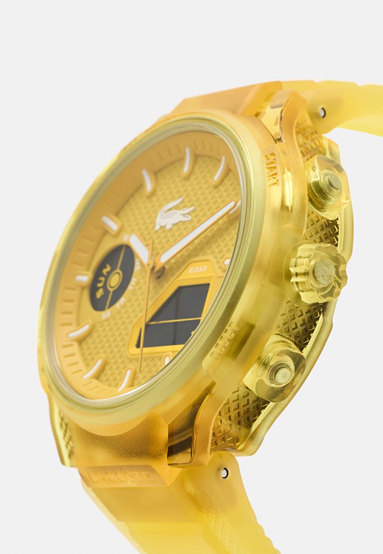 Reloj de pulsera amarillo con esfera texturizada, marcadores de hora blancos, dial de día, botones laterales y pantalla digital parcial, mostrado en ángulo.