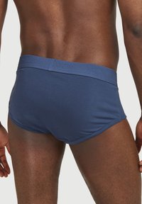 Herrarnas marina blå kalsonger i boxerstil, tillverkade av ett mjukt tyg med ett elastiskt band som har ordet "MEN" präglat. Sittande design, medelhög skärning.