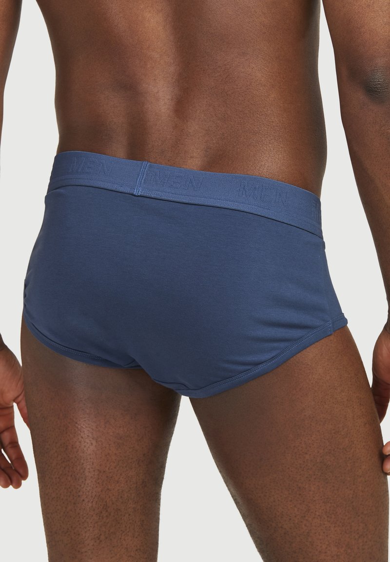 Herrarnas marina blå kalsonger i boxerstil, tillverkade av ett mjukt tyg med ett elastiskt band som har ordet "MEN" präglat. Sittande design, medelhög skärning.