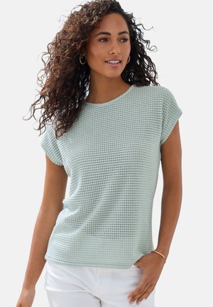 Helle mintgrüne Strick-T-Shirt mit strukturiertem Muster, kurzen Ärmeln, rundem Ausschnitt und lässigem Schnitt, kombiniert mit weißen Hosen.