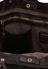 Interno di una borsa a tracolla in pelle marrone con tasca con zip, rivestimento in tessuto e una texture liscia. Presenta un'etichetta e chiusura a scatto.