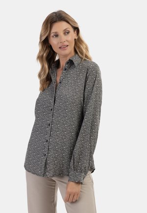 Camicia abbottonata nera con motivo floreale bianco. Presenta maniche lunghe con polsini abbottonati, un colletto classico e una vestibilità morbida.