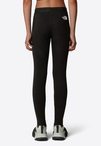 Svarta leggings med en bred, märkeslogotyp i midjan. Tillverkade av stretchmaterial, de har en jämn textur och en figursydd design.