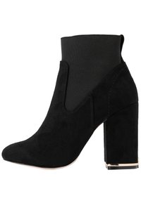 Stivaletto nero con esterno in suede e tacco blocco spesso. Ha una punta arrotondata e pannelli laterali elasticizzati per una facile calzata.