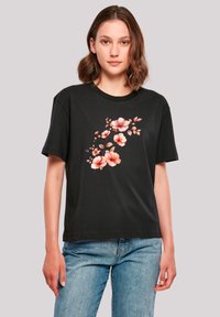 Schwarzes Baumwoll-T-Shirt mit kurzen Ärmeln, das ein florales Design in Rosa- und Orangetönen zeigt, das auf der Vorderseite zentriert ist.