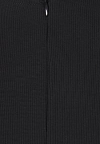 Tissu noir côtelé avec une couture verticale au centre et un petit bouton noir brillant près du bord supérieur.