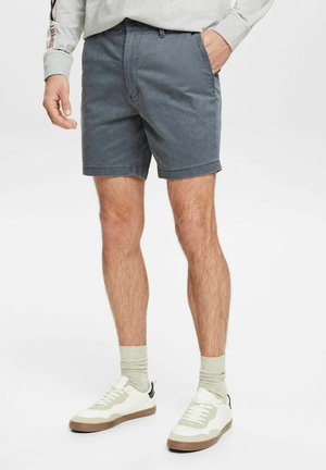 Grå bomulds shorts med lige snit og opsmøget kant, parret med hvide sneakers og lysegrå sokker. Enkel design og afslappet pasform.