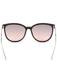 Gafas de sol tipo gato con un marco negro brillante, lentes degradados en rosa y delgadas varillas metálicas en color rosa dorado. Textura suave y forma audaz.